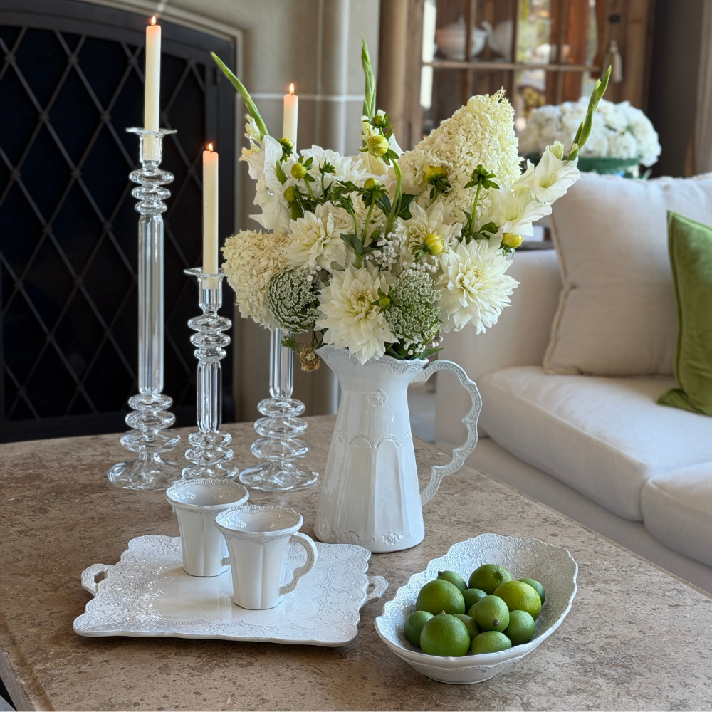 Table with Merletto Antique Scalloped pitcher with white flowers and Limes in an oval serving bowl with a square platter with Mugs