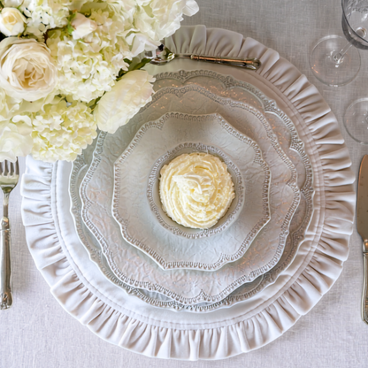Stacked Arte Italica Merletto antique plates on a table with flowers, including scalloped charger, dinner and salad plates