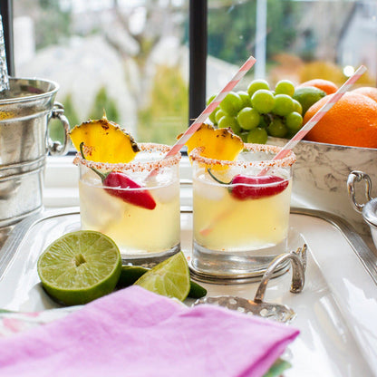 Two Arte Italica Milano Double Old Fashioned glasses styled as tropical cocktails with pineapple and cherry garnish on a silver tray