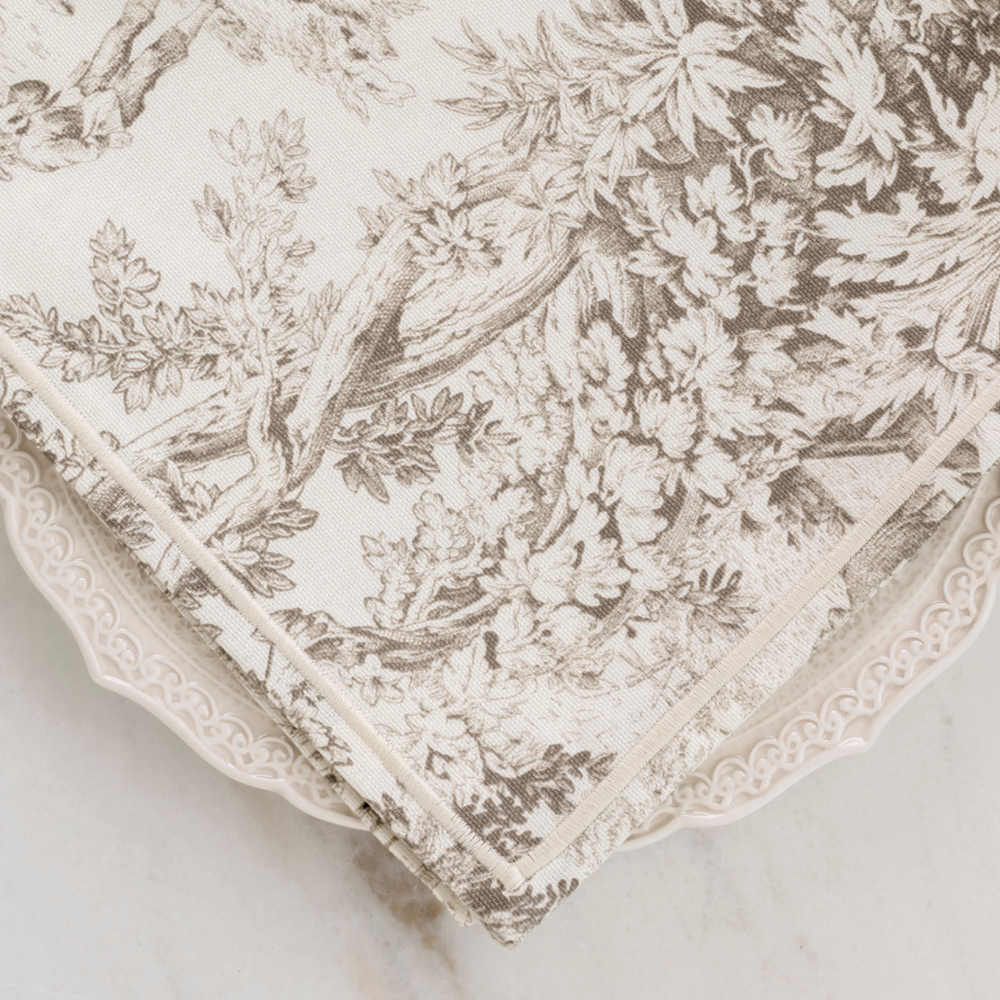 A latte brown montefalco toile cotton napkin on a Firenze plate on a marble table