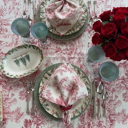A table with a Montefalco tablecloth set with Natale plates and Montefalco Red cotton napkin with roses