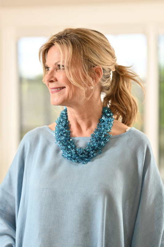 Detailed shot of woman wearing blue crystal cluster necklace. --Arte Italica and Crown Linen Designs