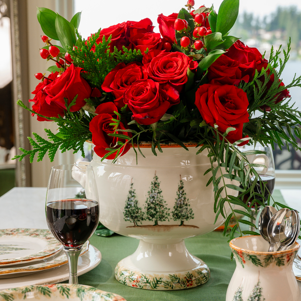 A Natale hand painted Italian ceramic pedestal bowl with red roses on a table set with Natale dinnerware
