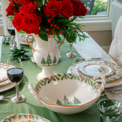 Natale ceramic twist handle bowl shown from the top with the Natale pine pattern around the edge and 3 hand painted pine trees on a table set with Natale and a Urn with red roses