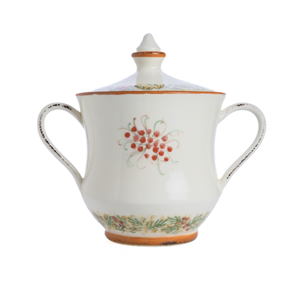 A two handled cookie jar with lid in the Arte Italica Natale pattern with red berries painted on it on a white background