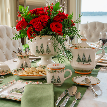 A table set with Natale plates on green runner with Lidded cookie jar, Tea Infuser Mug, Small Cachepot with red roses and small Vase