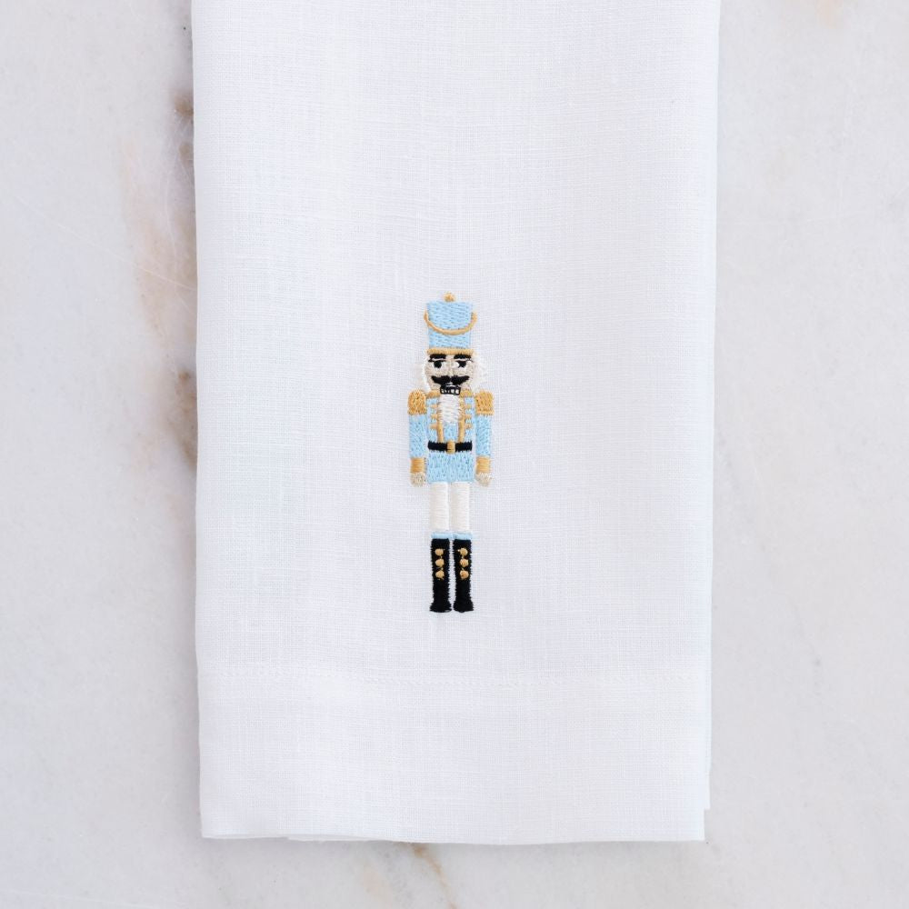 Decorative white linen towel with our 2026 nutcracker in Blue on a white background on a marble table - Crown Linen Designs