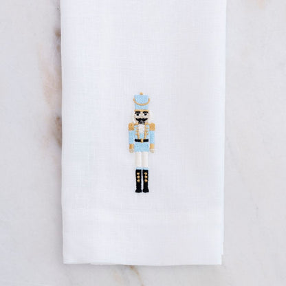 Decorative white linen towel with our 2026 nutcracker in Blue on a white background on a marble table - Crown Linen Designs