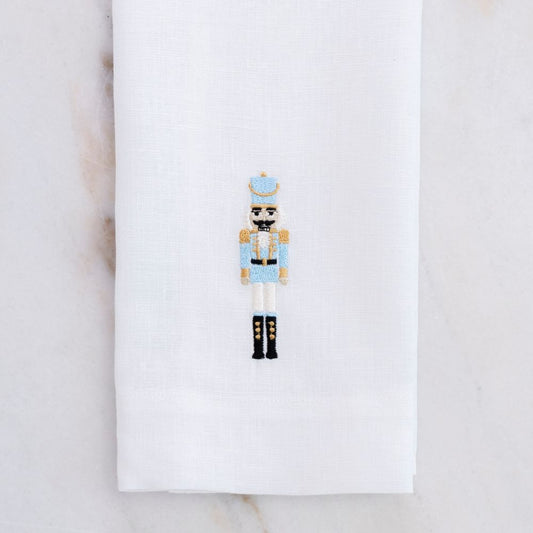 Decorative white linen towel with our 2026 nutcracker in Blue on a white background on a marble table - Crown Linen Designs