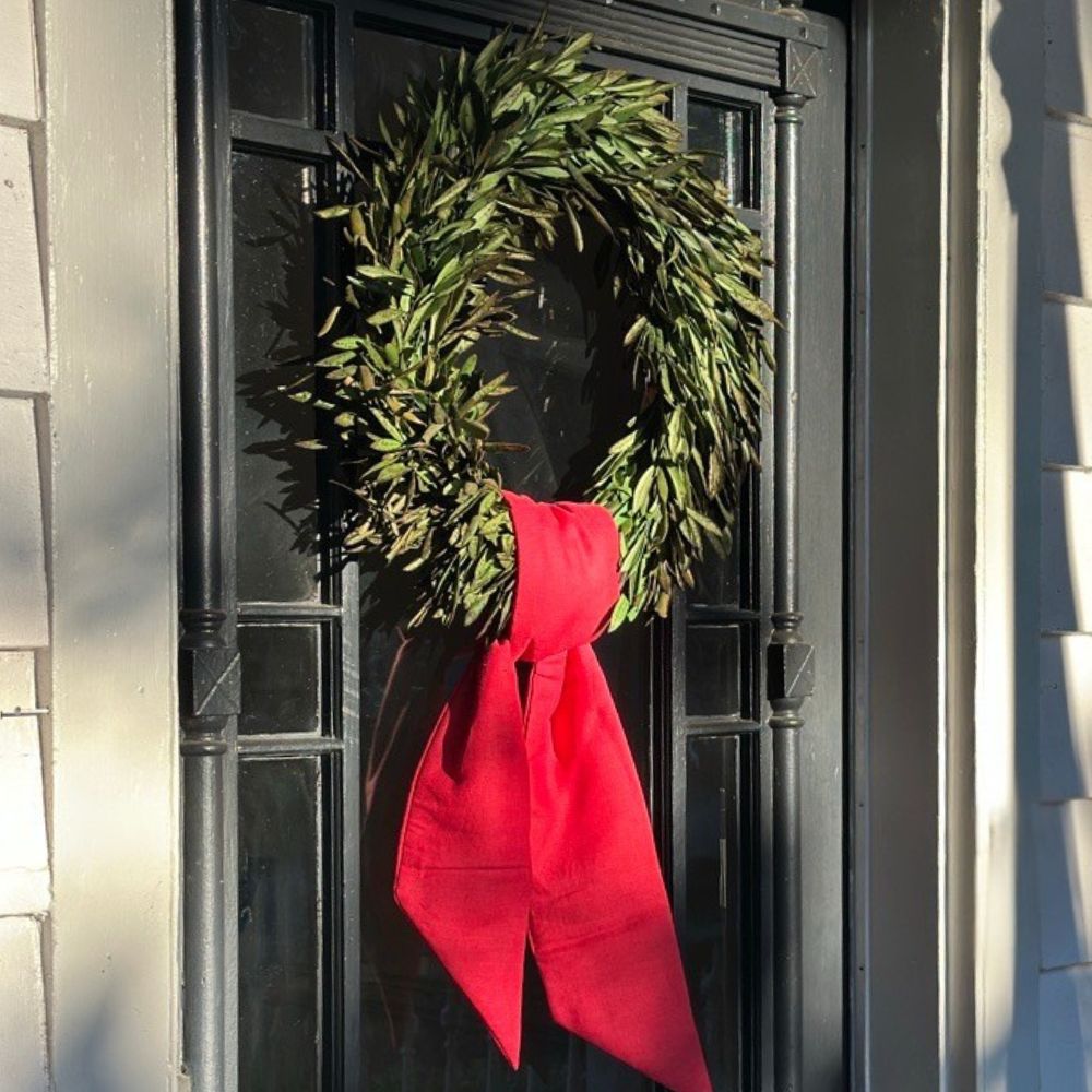 Green wreath with a red bow on a black door