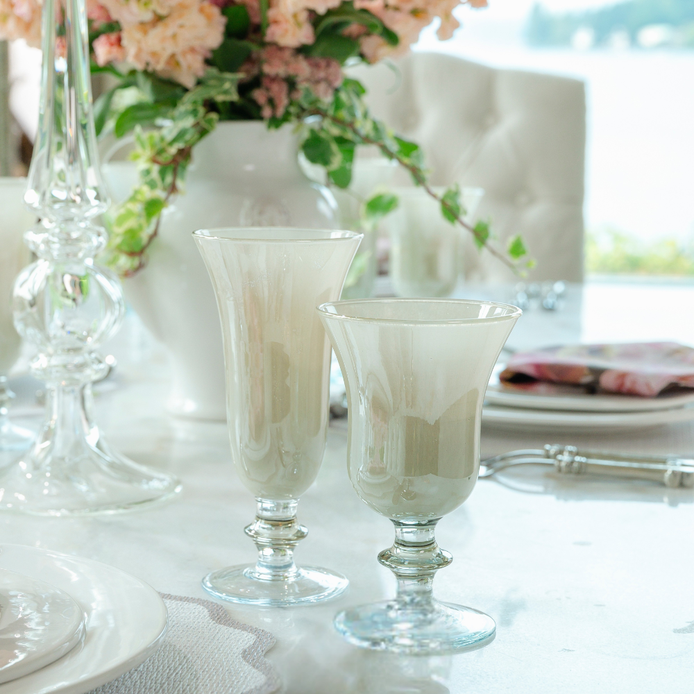 Rialto taupe flute glass and water wine glass on a white table with flowers in the background