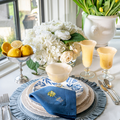 Rialto hand painted Italian Glass Compote in Yellow with Flute and Wine Glass on a table with Place setting and flowers