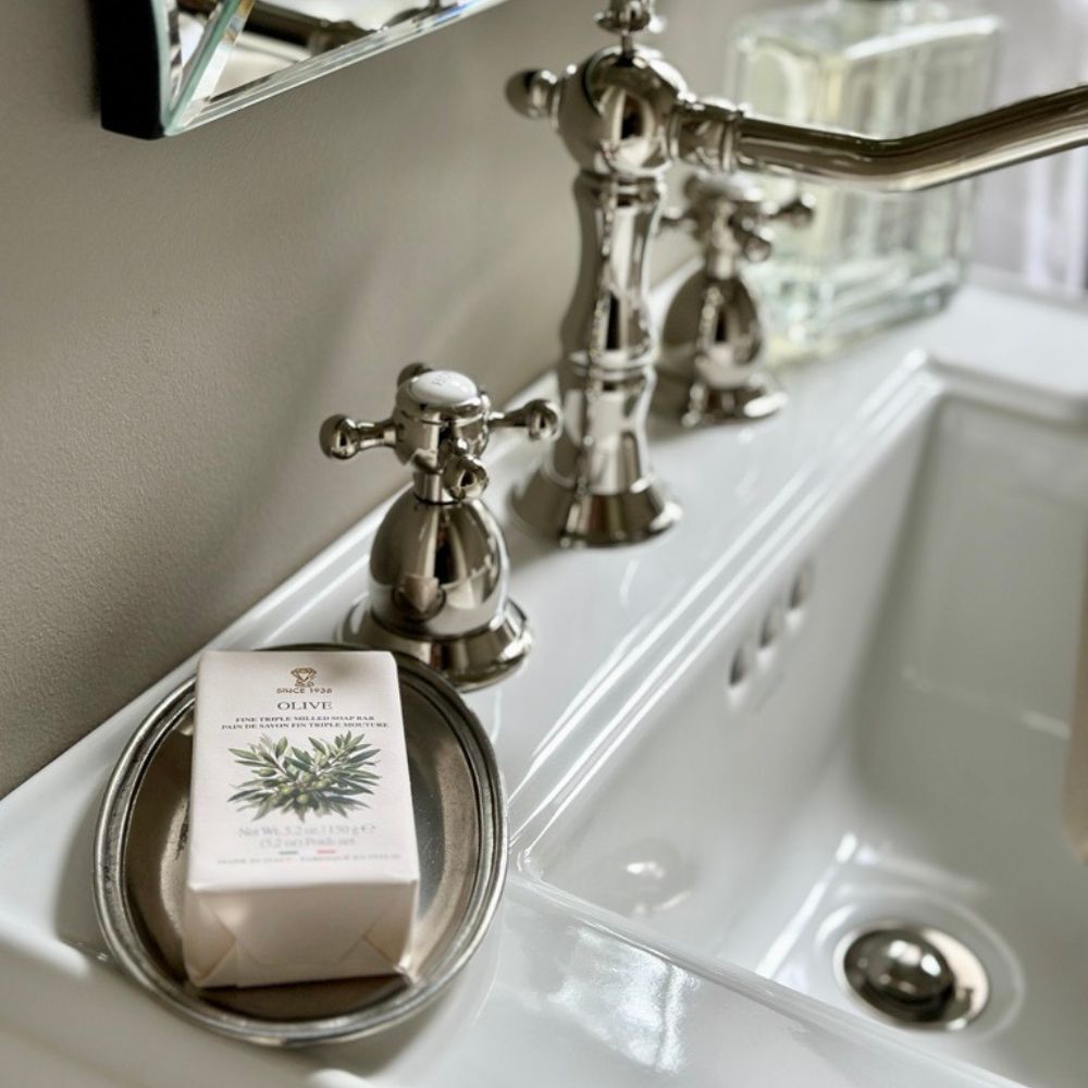 Roma Small Pewter Oval Tray Soap dish with a bar of soap on a bathroom sink with silver faucet.