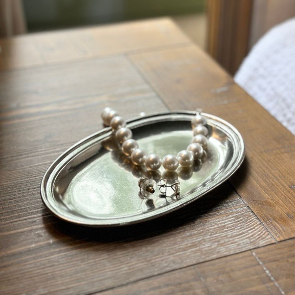 Pearl bracelet on a Roma Pewter tray on a wooden table