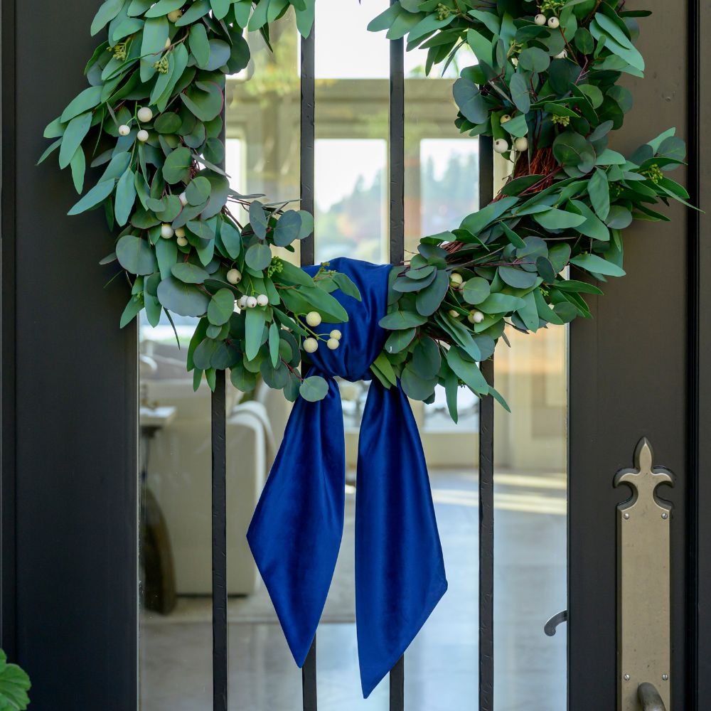 Green wreath with a royal blue velvet bow on a door