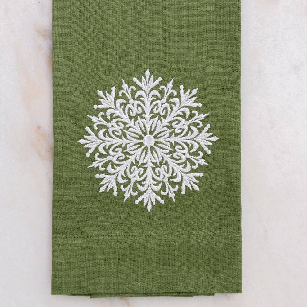 Green linen towel with a white snowflake design on a marble surface