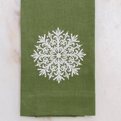 Green linen towel with a white snowflake design on a marble surface