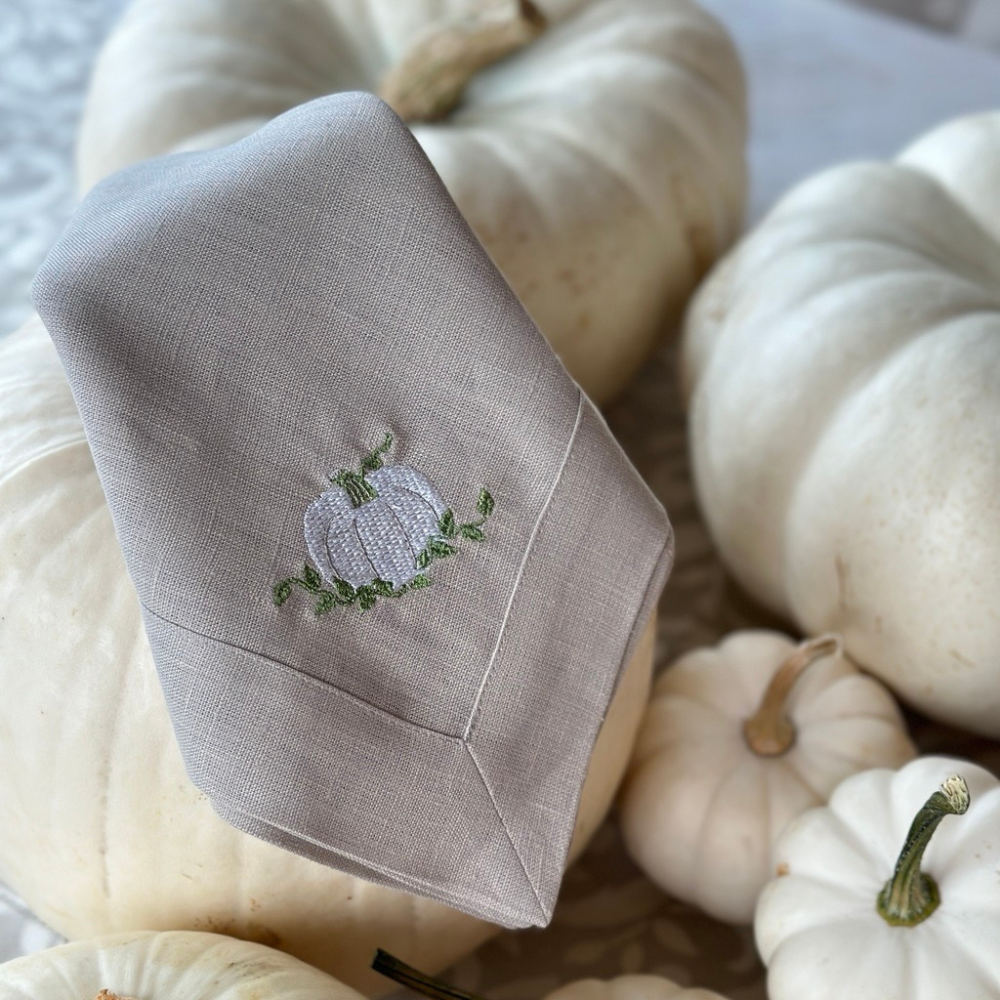 Soft Flax Linen napkin with embroidered pumpkin design on a background of white pumpkins