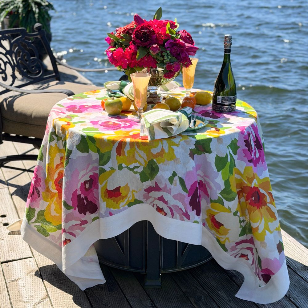 Portofino Summer Garden Table Square — Table with a linen floral tablecloth by a body lake, set for a celebration.