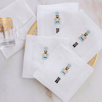 White napkins with embroidered nutcracker designs on a marble surface.