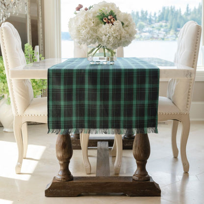 Dining table with a green plaid tablecloth and white flowers in a vase.