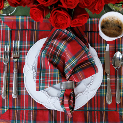 Plaid table setting with red roses, white plates, and silverware on a plaid tablecloth.