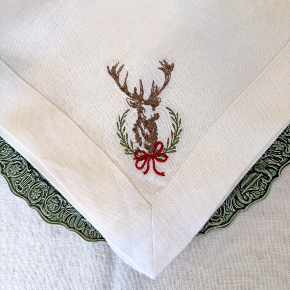 Embroidered linen napkin with a deer design on a white background