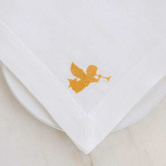 White linen napkin with gold angel embroidery on a beige background