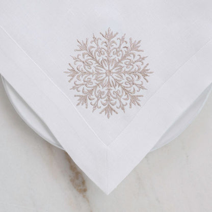 White linen napkin with a gold embroidered snowflake design on a light background