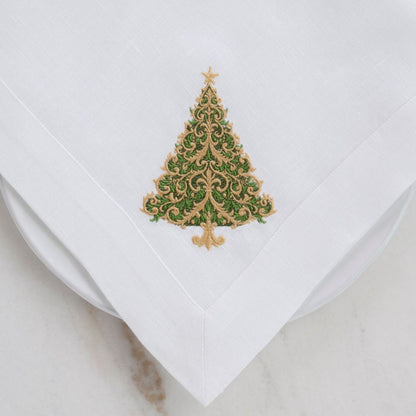 White linen napkin with a decorative green and gold Christmas tree design on a light gray background