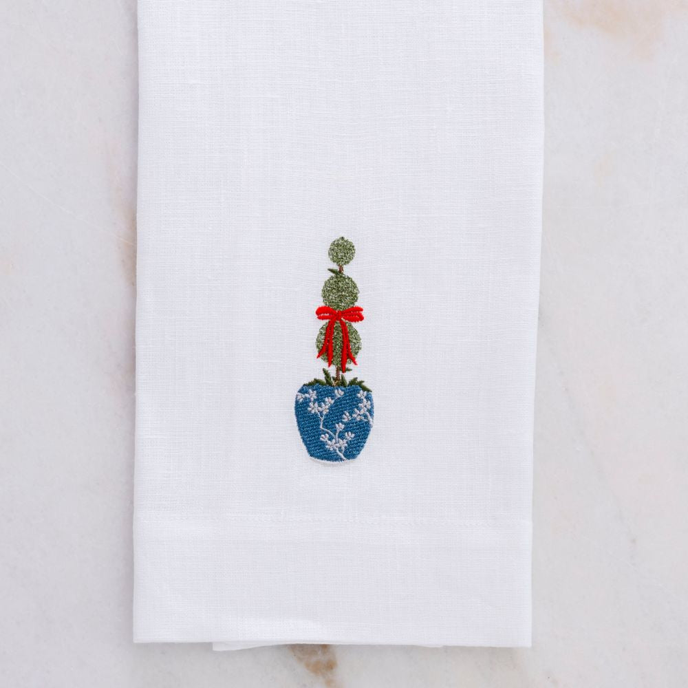 White linen towel with embroidered topiary design on a marble surface