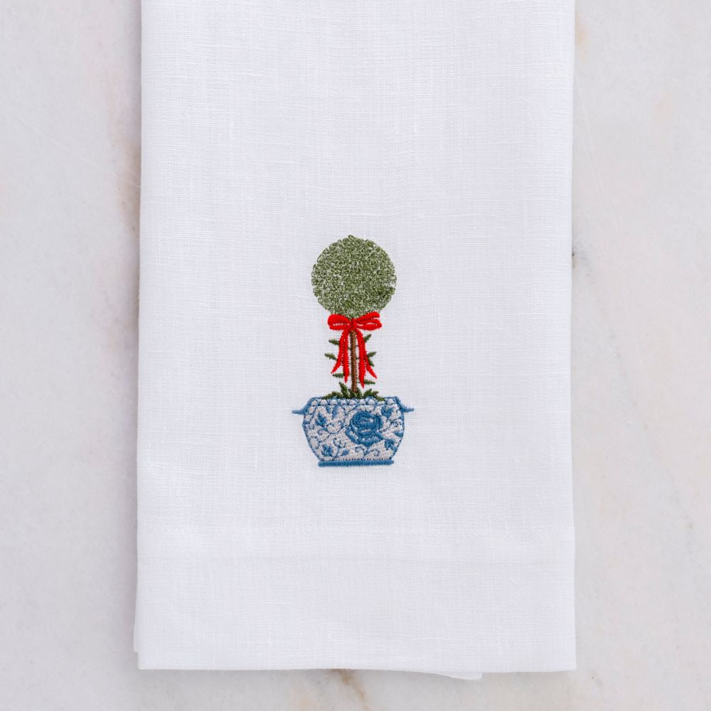 White towel with embroidered topiary design on a marble surface