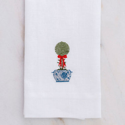 White towel with embroidered topiary design on a marble surface