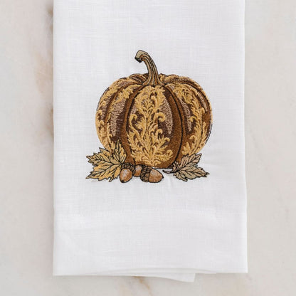 White linen towel with embroidered pumpkin design on a white background