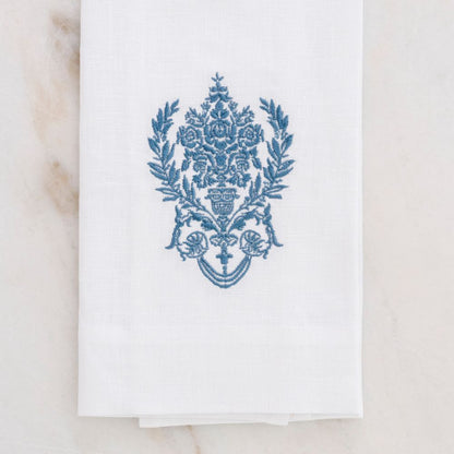 White towel with blue decorative emblem on a marble surface