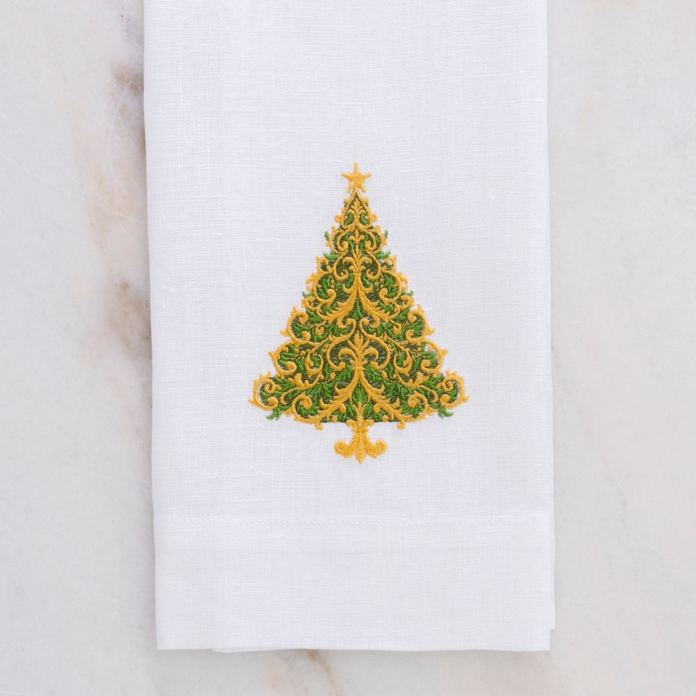 White linen towel with a decorative green and gold Christmas tree design on a marble surface.