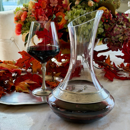Taverna wine decanter with pewter ring filled with red wine and a Siena wine glass on a table with flowers