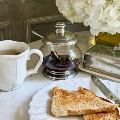 Tavola Covered Bowl with Spoon on a table with Bella Bianca mug and toast on a plate with white flowers