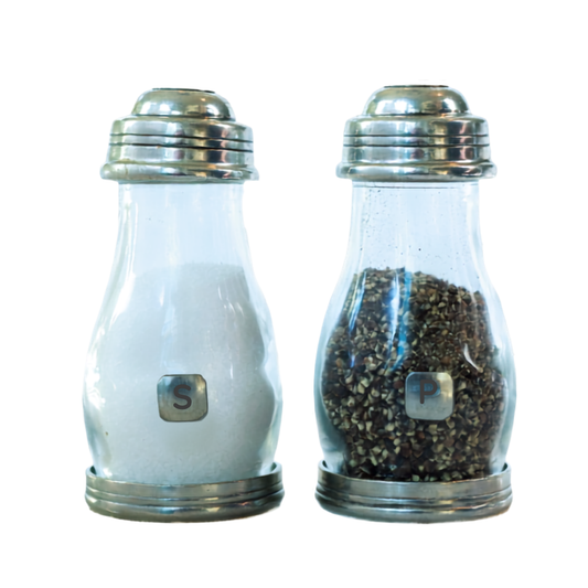 Two clear glass pepper and salt shakers with pewter metal caps and bases, shown side by side on a white background. The left shaker contains white salt, and the right shaker contains dark ground pepper.
