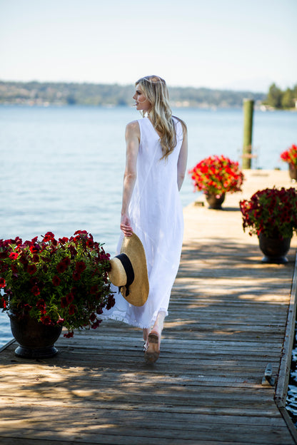 Back view of white linen Twani dress on woman walking down a doc. --Arte Italica and Crown Linen Designs