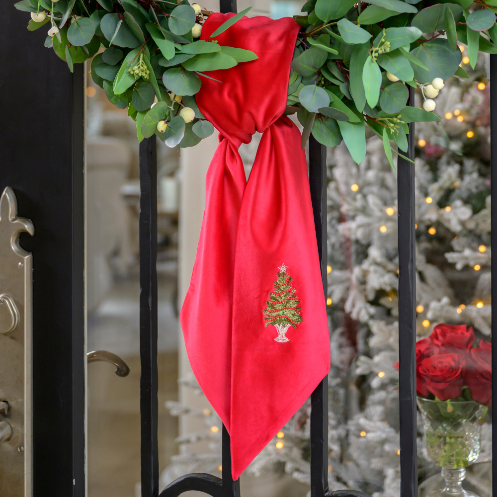 Decorative wreath with a red Velvet Tree with Trim Bow on a black metal door by Crown Linen Designs