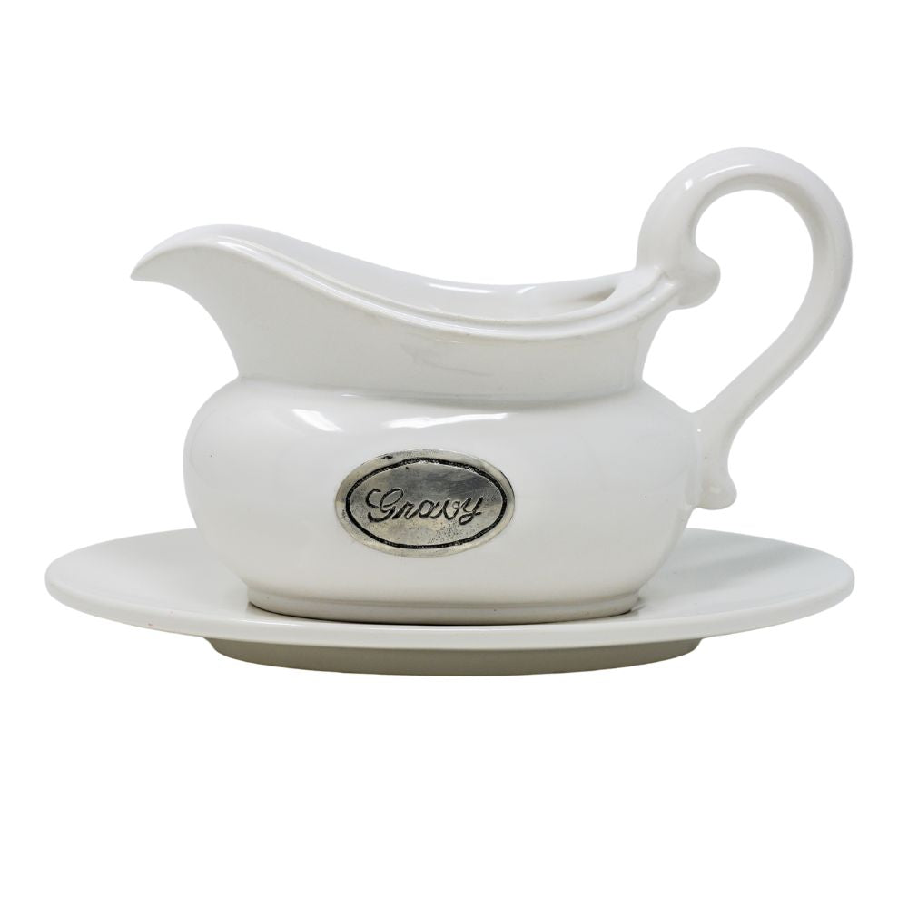 White ceramic gravy boat with pewter tab with a matching saucer on a white background
