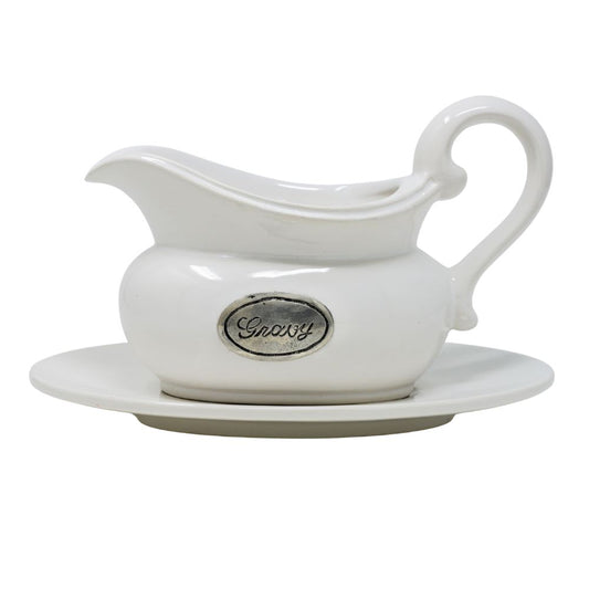 White ceramic gravy boat with pewter tab with a matching saucer on a white background