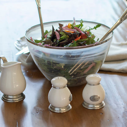 Tuscan ceramic salt and pepper set on a wood table in front of a salad