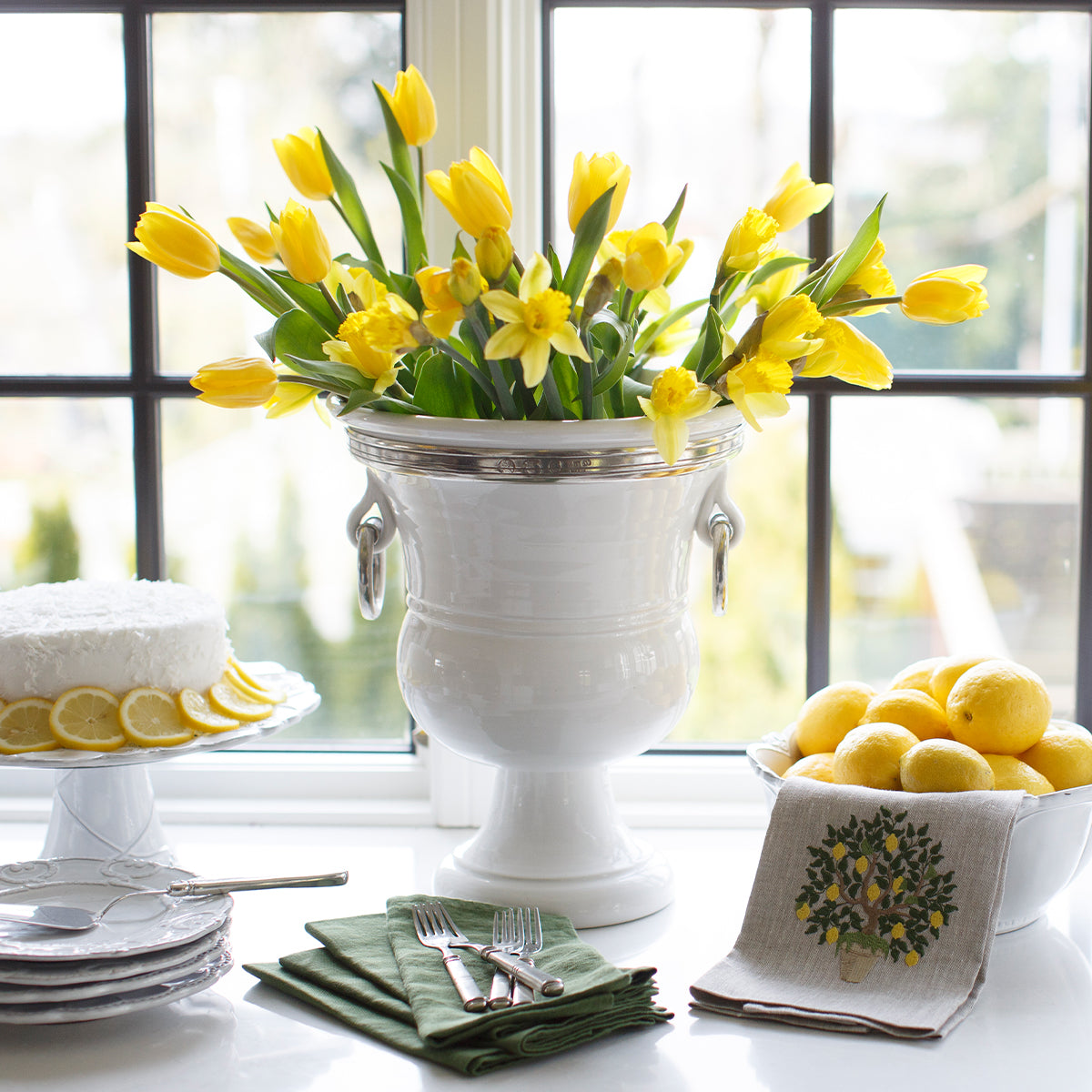 Tuscan Signature Urn on counter with daffodils and yellow tulips and plates and a cake