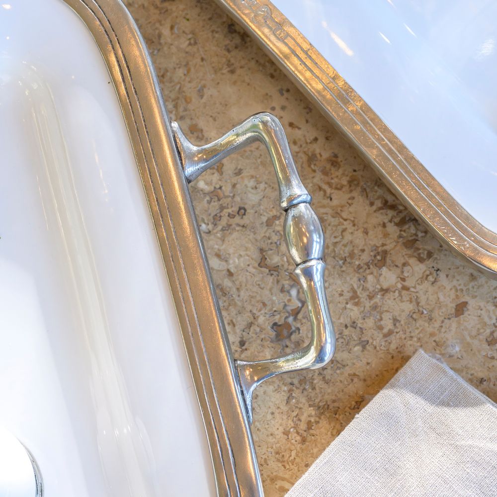 Close-up of a Tuscan Pewter tray with a decorative handle on a marble surface.