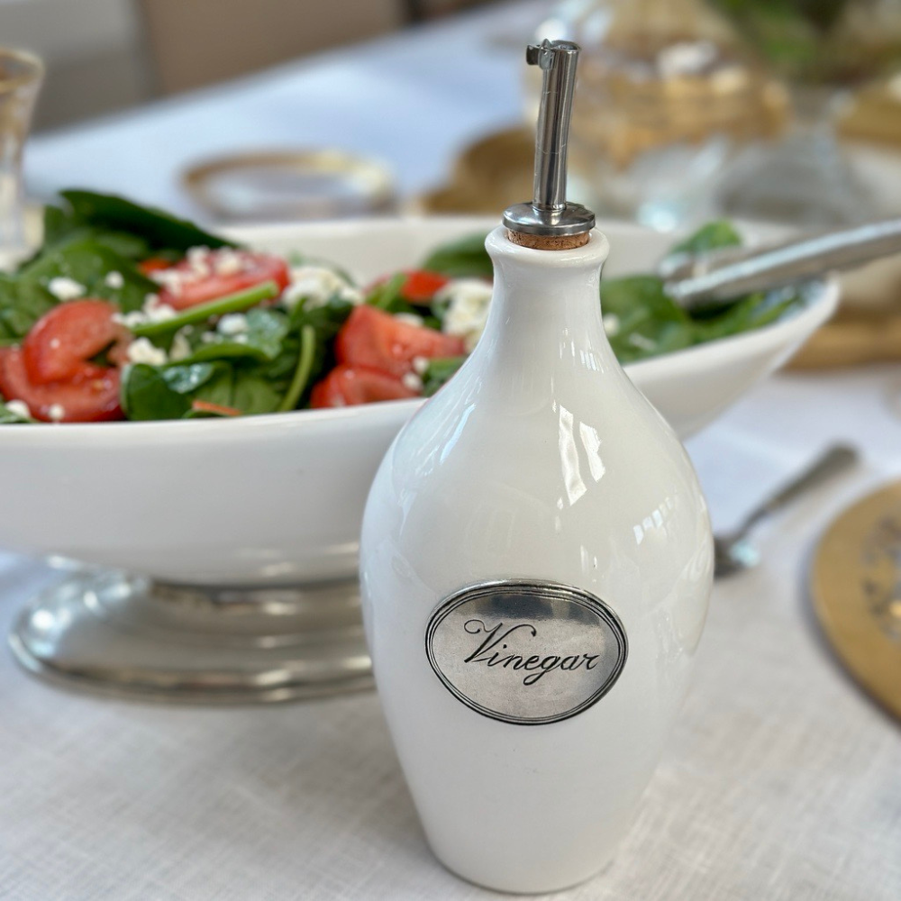 Tuscan ceramic vinegar bottle with spout on table by a green salad