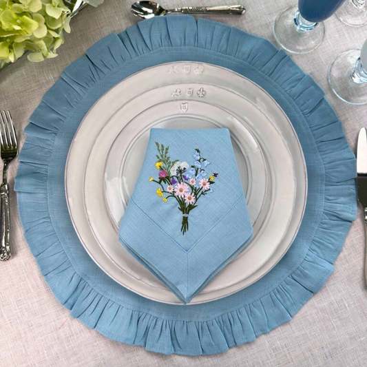 Blue ruffle placemat styled with firenze plates and floral blue napkin. 