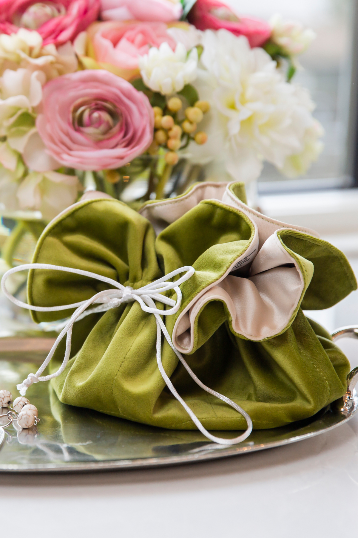 Pear velvet jewelry blossom pouch with white drawstring cord on silver tray, styled with spring flowers