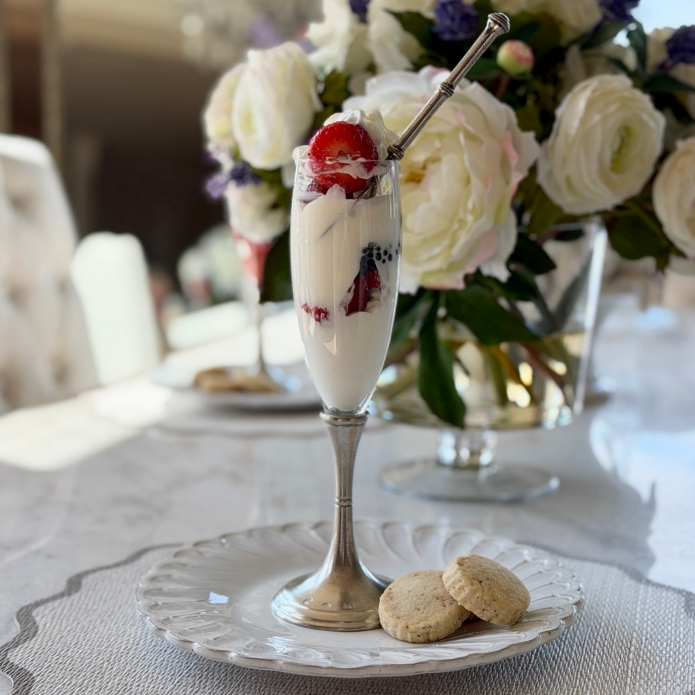 A Verona aperitif glass with pewter stem on a Bella Bianca plate filled with ice cream and fruit with some cookies on a white table